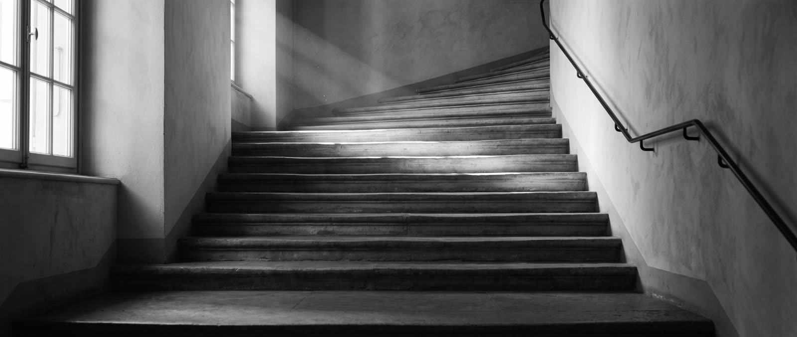 Escalier de pierre d’un immeuble ancien, la lumière du jour sur les marches.
